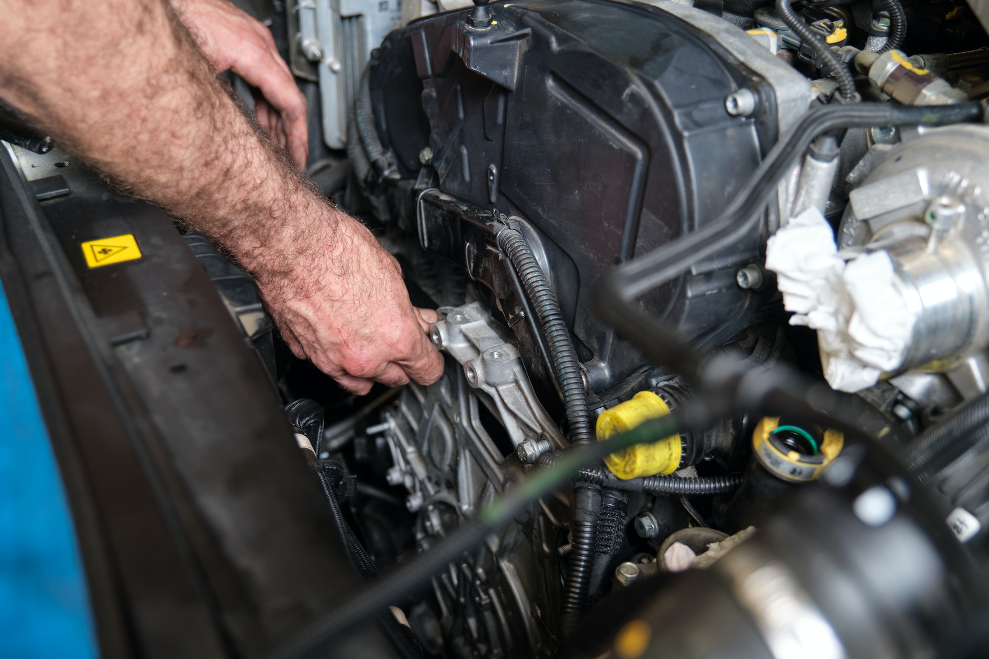Les mains du mécanicien automobile vissent le support moteur après avoir remplacé la courroie de distribution. 
