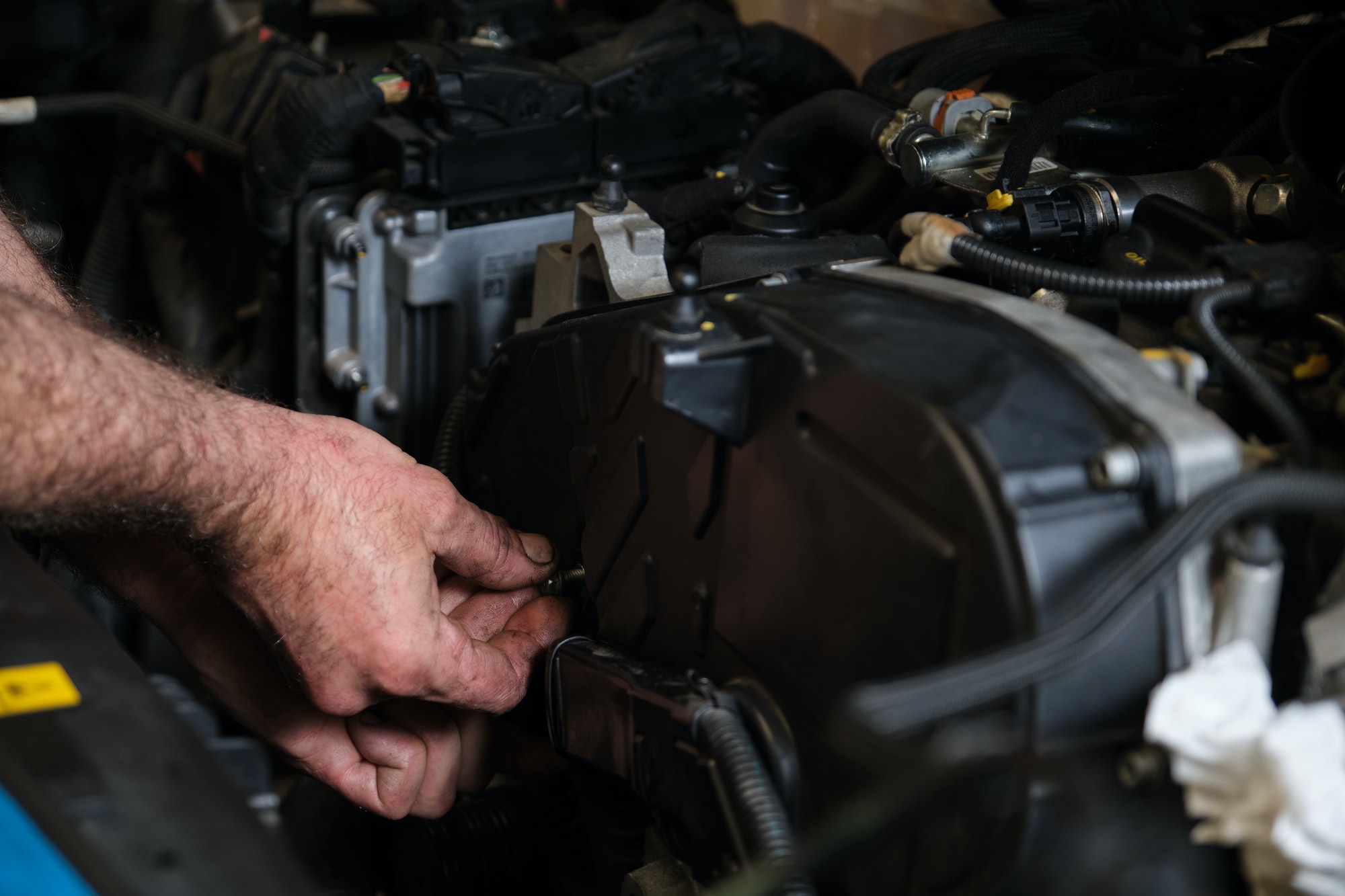 Les mains du mécanicien automobile dévissent le support moteur pour remplacer la courroie de distribution.